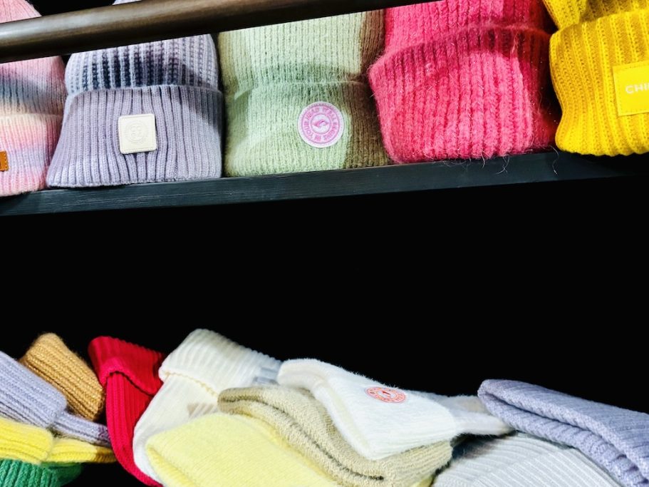 „Gestapelte Strickaccessoires und winterliche Mützen in Pastellfarben.“