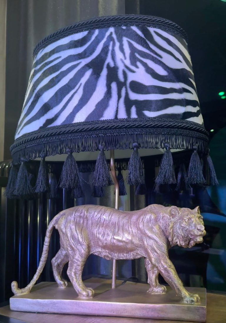 Dekorative Tischlampe mit gemustertem Lampenschirm und Tigerfigur auf Sockel
