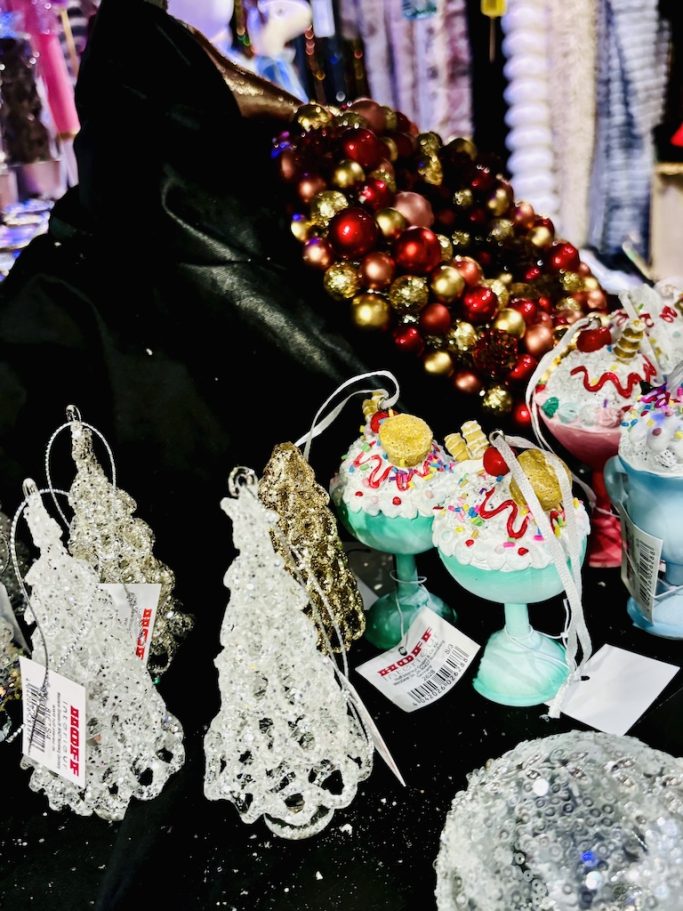 „Weihnachtliche Dekoanhänger und bunt verzierte Figuren auf schwarzer Präsentationsfläche im BSix® Conceptstore.“