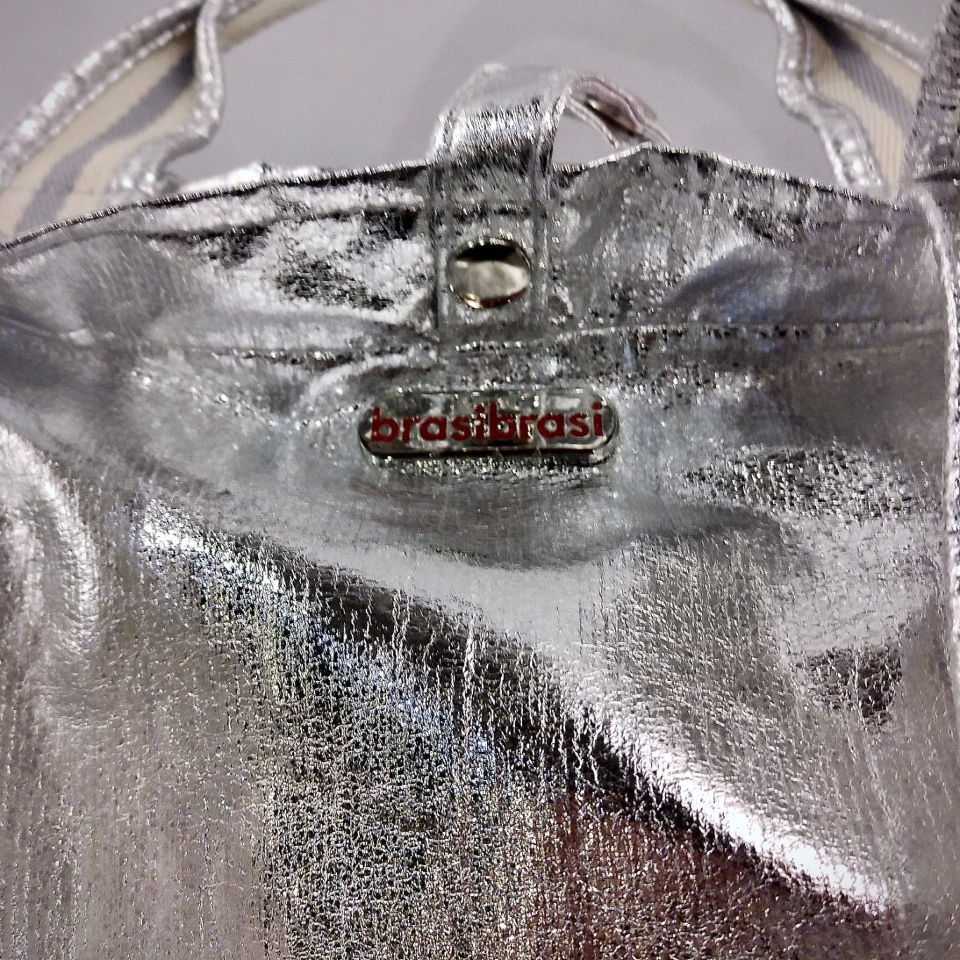 Metallic beschichtete Tasche in Silber mit kurzen Henkeln, Frontansicht mit Logo, aus dem Sortiment des BSix Conceptstores
