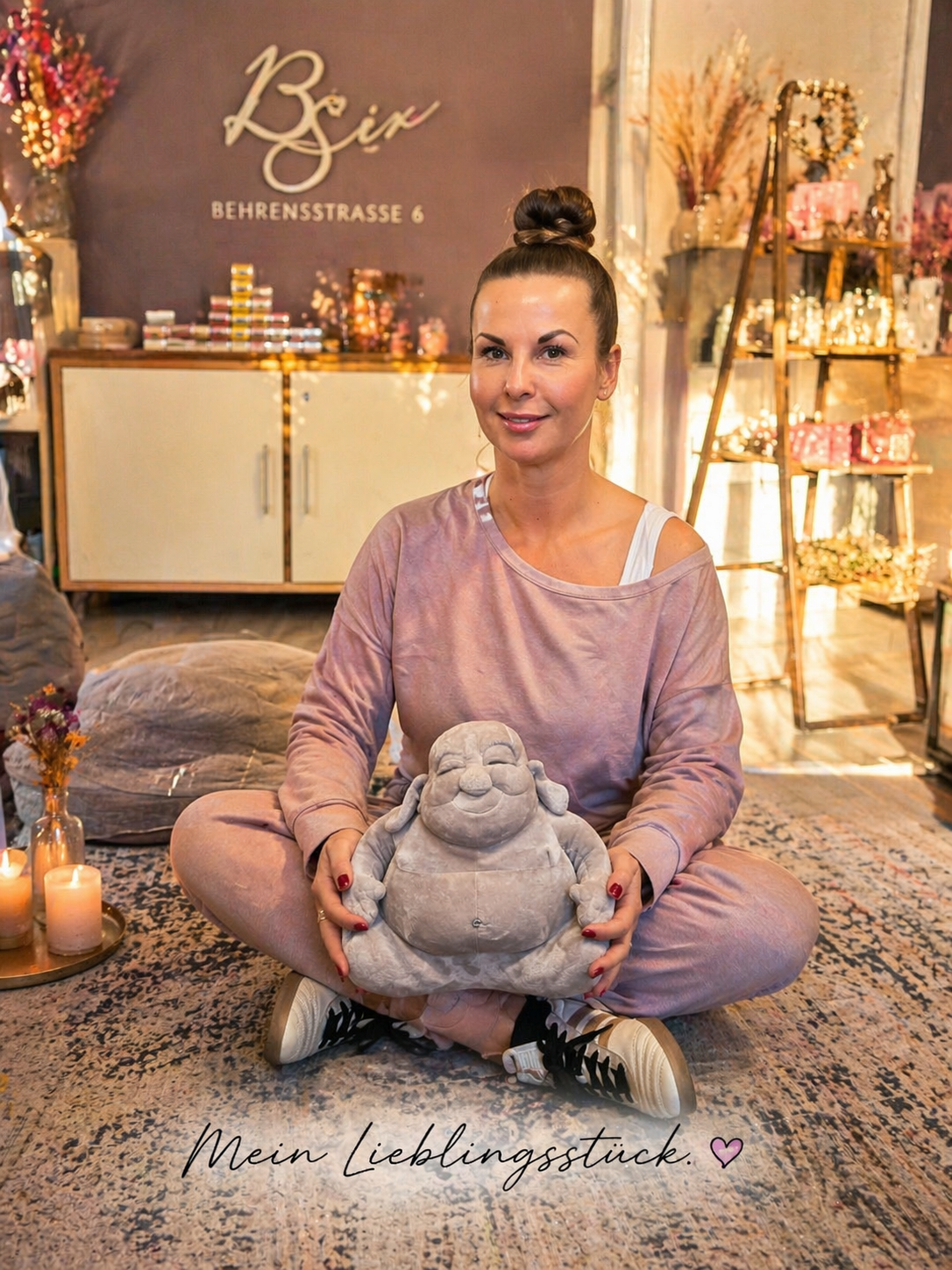 Frau sitzt in einem Raum mit Dekoration und hält eine Buddha Figur als Produktdarstellung
