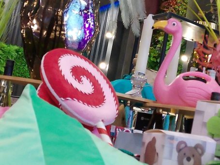 „Dekoarrangement im BSix® Conceptstore mit großem rosafarbenen Flamingo, farbigen Kunstblumen und einer dekorativen Spirale in Rot und Weiß.
